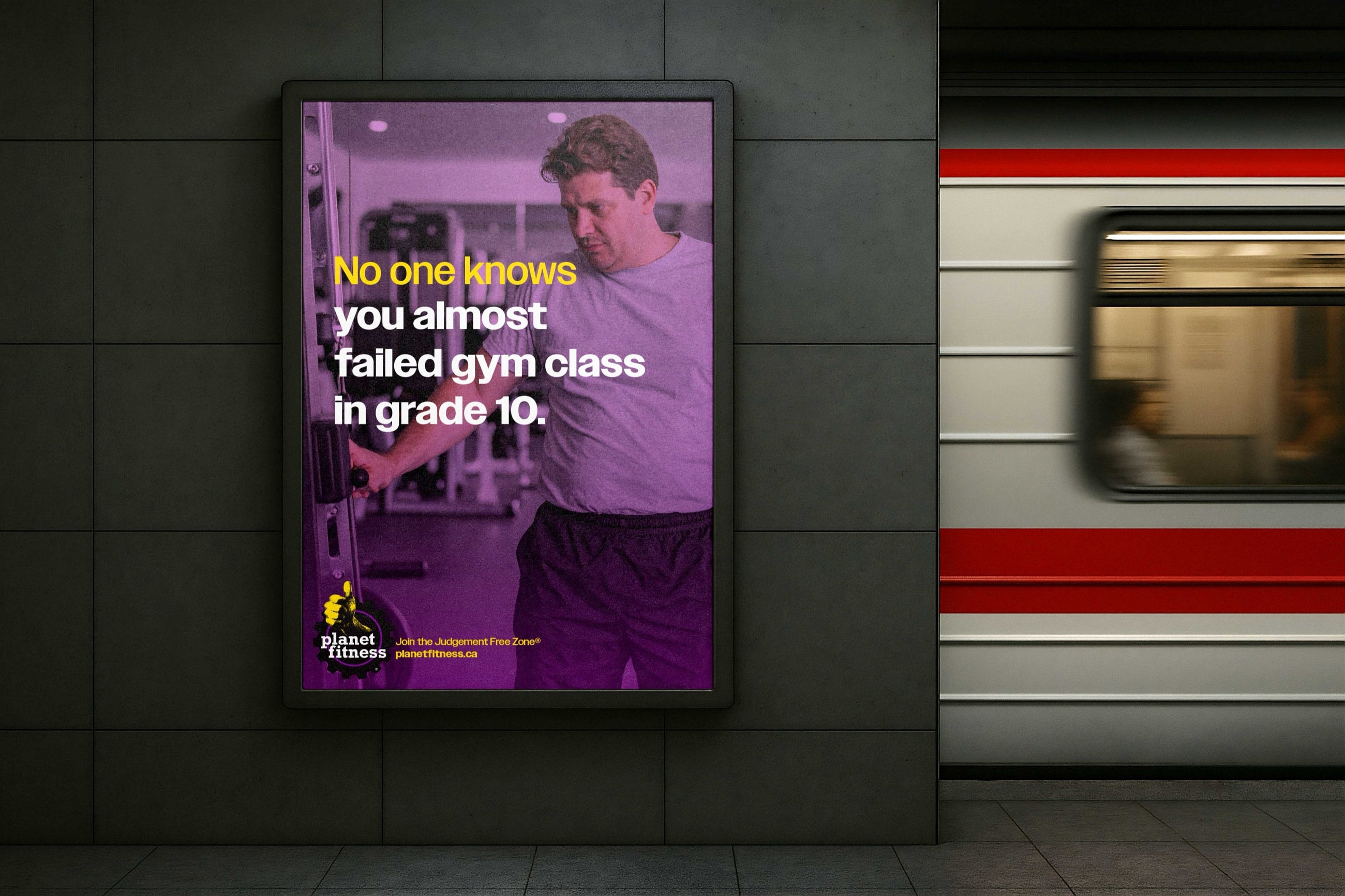 Subway poster on a tiled platform, a train blurring past: a man at a cable machine, in purple. No one knows you almost failed gym class in grade 10. Join the Judgement Free Zone®.