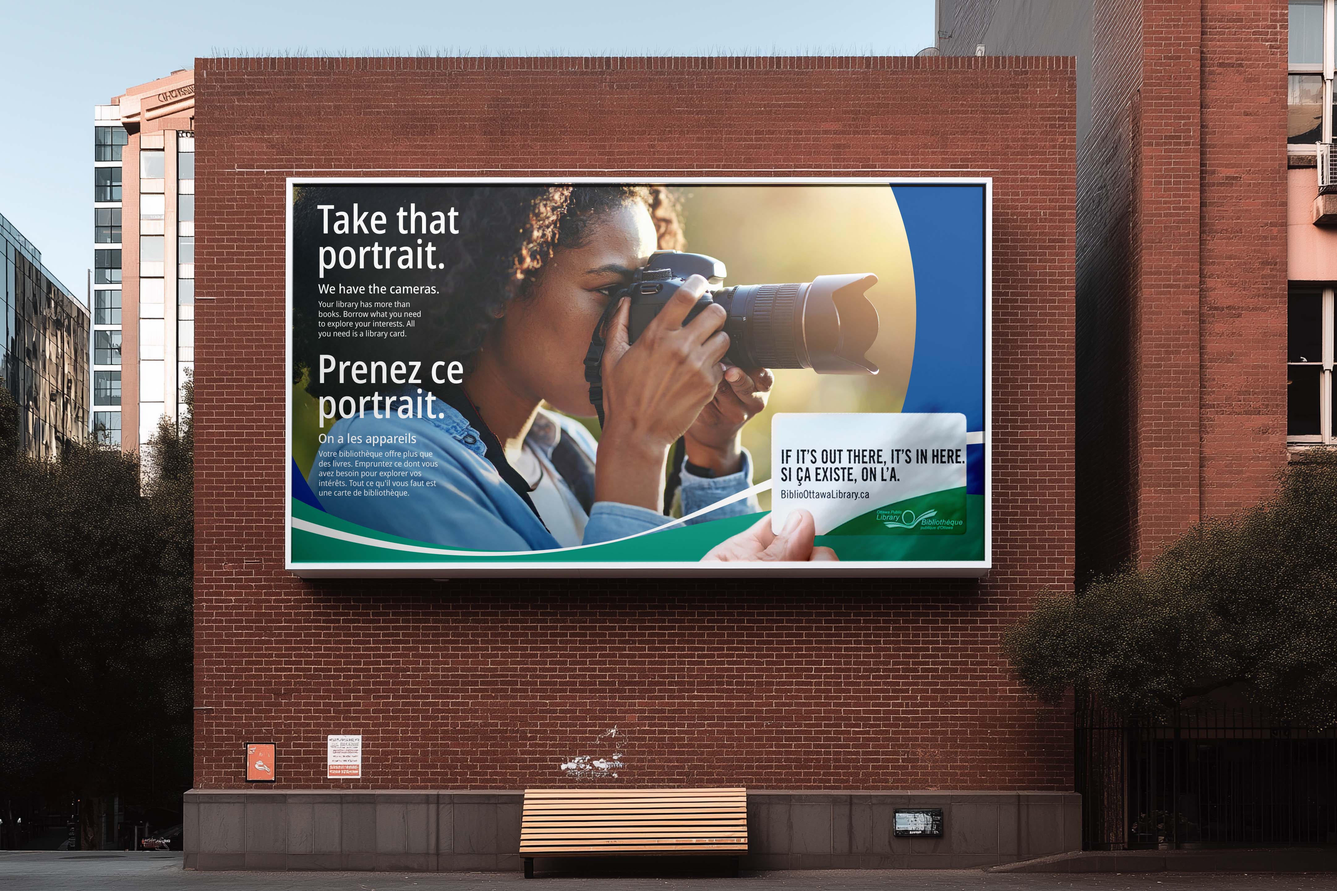 Large outdoor billboard featuring woman with camera and bilingual campaign messaging encouraging creative exploration